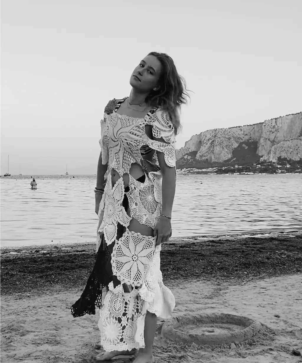Schwarzweiß: Model in einem Kleid aus zusammengesetzter Häkelspitze am Strand